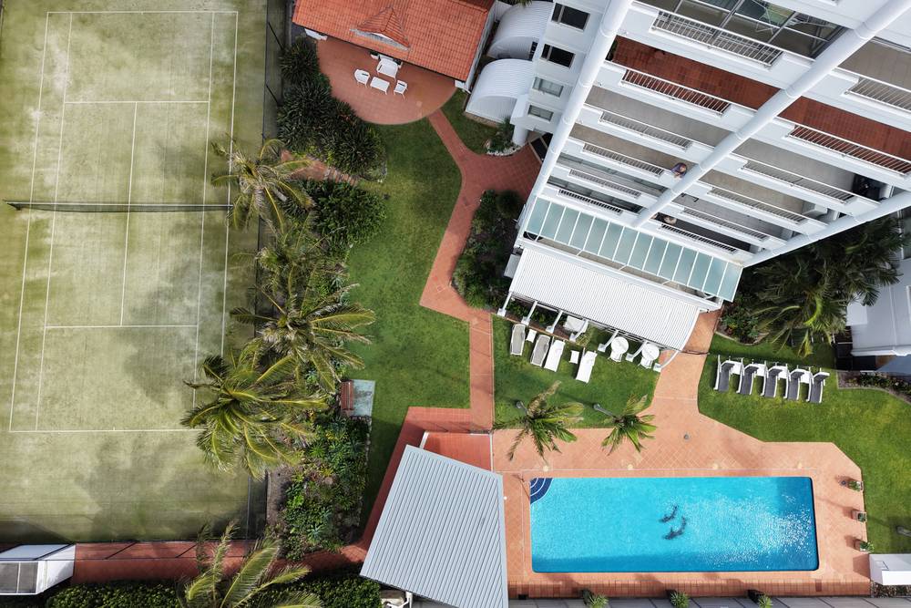 Pool and tennis court among red pavers