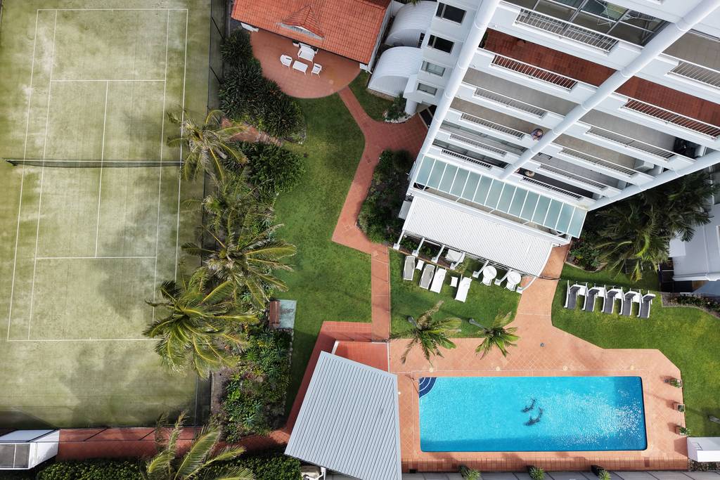 Pool and tennis court among red pavers