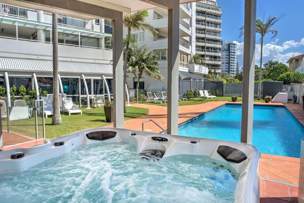 Outdoor spa with jets and seating, swimming pool and covered pavilion visible